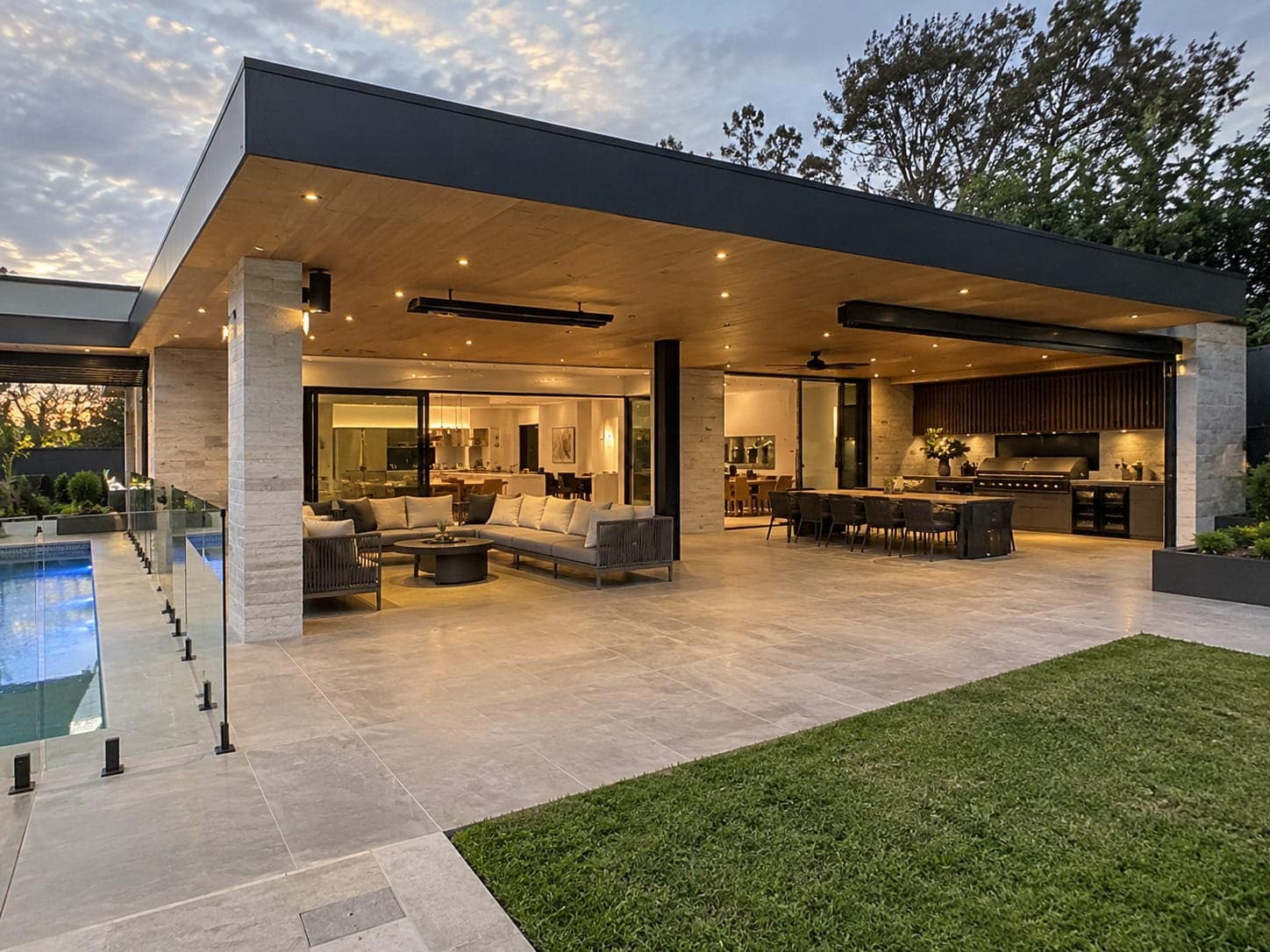 Covered concrete alfresco with an outdoor kitchen beside a pool in Aranda, ACT
