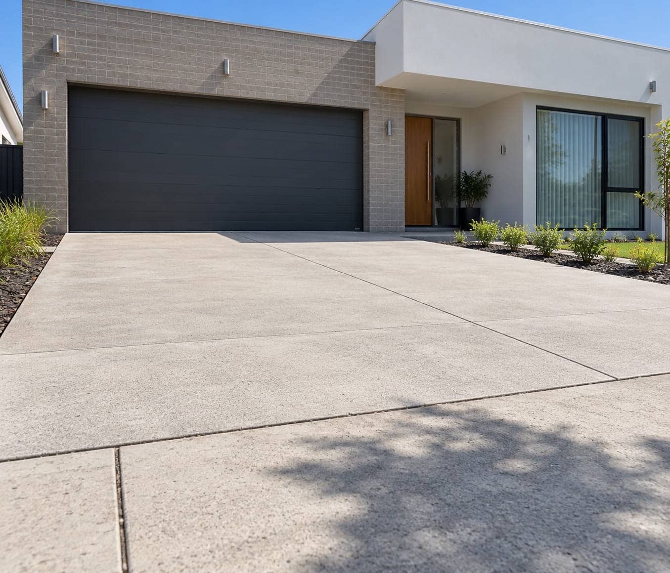 Broom-finished concrete driveway leading to a double garage in Coombs, ACT