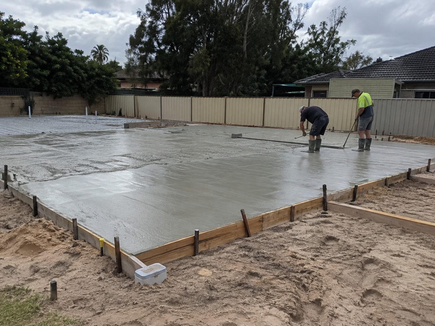 Concreters screeding a freshly poured house slab in formwork