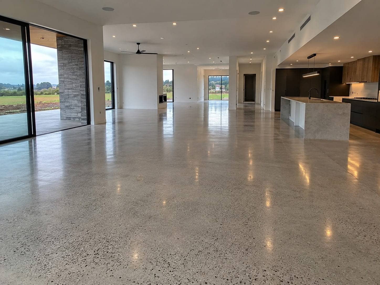 Honed concrete floor with fine exposed stone running through the open-plan living and kitchen of a new Canberra home