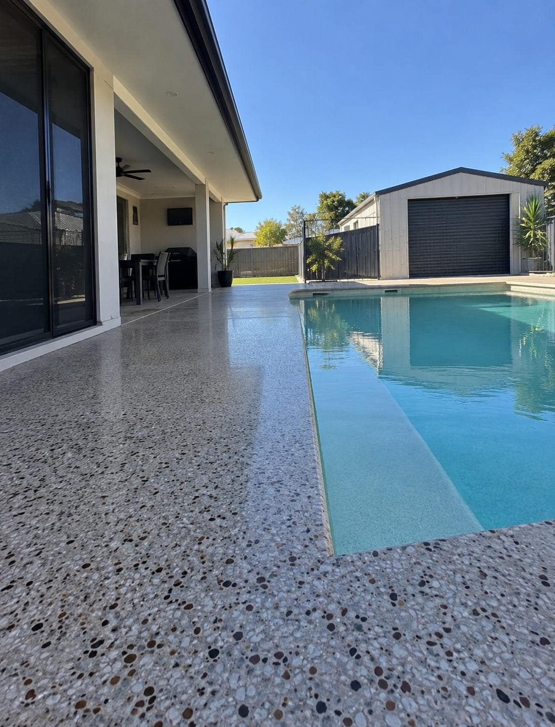 Light-toned coloured concrete pool surround beside a Canberra backyard pool